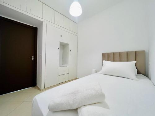 a white bedroom with a white bed and a cabinet at Appartement moderne à Martil in Martil