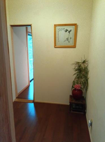an empty room with a plant and a picture on the wall at Akitsuki Kominka Yado You in Asakura