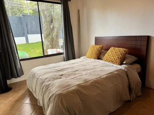 a bedroom with a bed with two pillows and a window at Charming house 5 min airport with Ac in Alajuela City