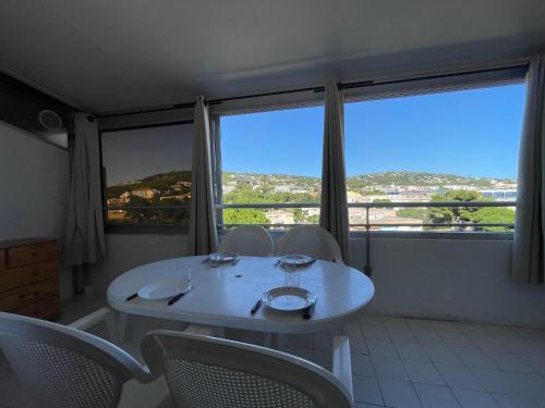 - une table et des chaises blanches dans une chambre dotée de grandes fenêtres dans l'établissement Studio Cabine à Sète: Véranda, Parking, Ascenseur, Plage à 300m - FR-1-338-44, à Sète