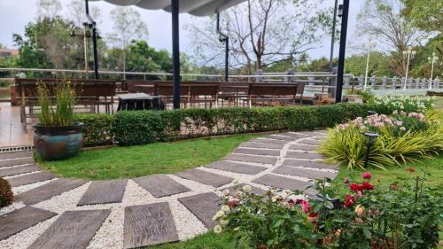 a garden with a stone pathway and flowers at Dhammachart RiverView in Samut Songkhram