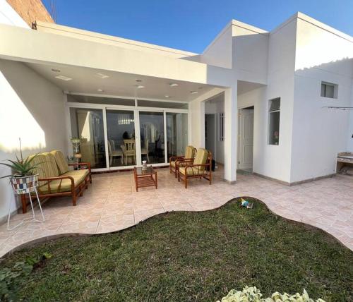 a house with a patio with chairs and a table at Hermosa casa a 15 min de Paracas in Pisco