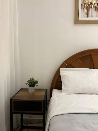 a bed with a wooden headboard and a table with a plant at Hermosa casa a 15 min de Paracas in Pisco