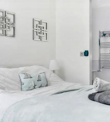 a white bed with blue pillows on top of it at Seaside Place on Shoreham Beach with Hot Tub in Shoreham-by-Sea