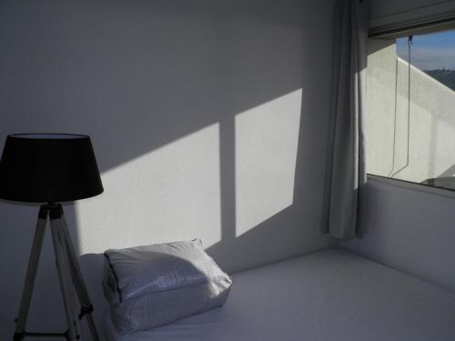 une chambre blanche avec une lampe et une fenêtre dans l'établissement Studio-mezzanine lumineux avec parking à 150m des plages, animaux bienvenus - FR-1-338-330, à Sète