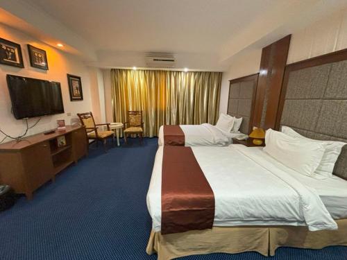 a hotel room with two beds and a desk and a television at Lido De Paris Hotel in Manila