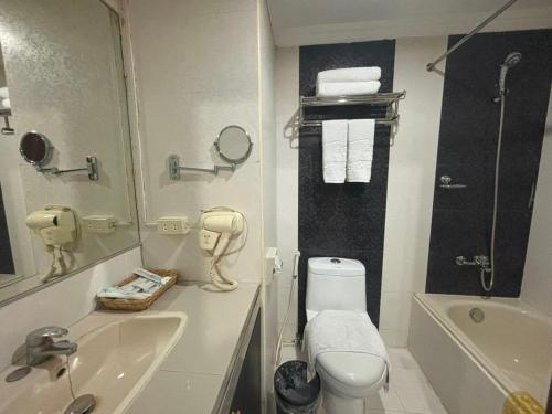 a bathroom with a toilet and a sink and a tub at Lido De Paris Hotel in Manila