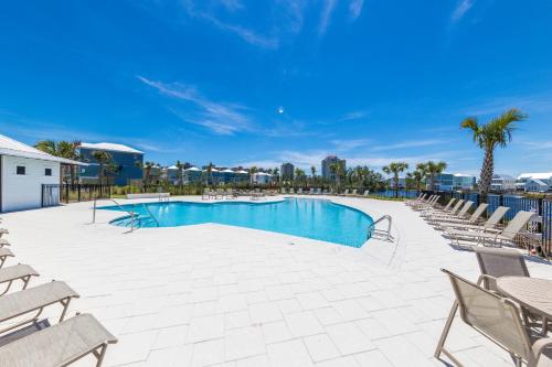 a large swimming pool with chairs and a blue sky at Whiskey Sands - Luxury by Gulf State Park, Great Views, Walk to Beach and Restaurants, Beautiful Pool, Fenced Yard! in Orange Beach