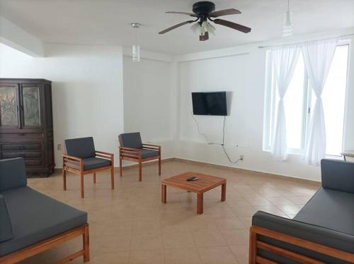 a living room with chairs and a tv and a table at Casa Fefe Huatulco in Tangolunda