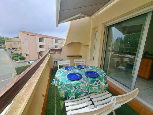une table et des chaises sur un balcon avec une table et des assiettes bleues dans l'établissement Accès direct plage! Charmant T2 mezzanine avec terrasse et parking privé - FR-1-326-833, à Marseillan