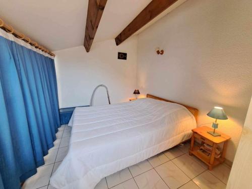 une chambre avec un lit blanc et un rideau bleu dans l'établissement Accès direct plage! Charmant T2 mezzanine avec terrasse et parking privé - FR-1-326-833, à Marseillan