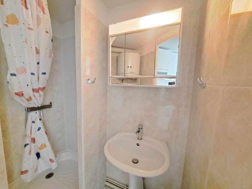 une salle de bain avec un lavabo et un miroir dans l'établissement Accès direct plage! Charmant T2 mezzanine avec terrasse et parking privé - FR-1-326-833, à Marseillan