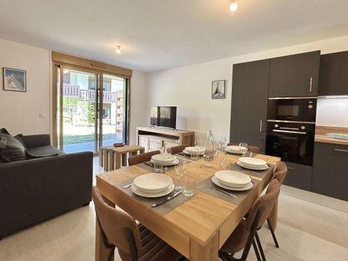 une cuisine et une salle à manger avec une table et des chaises dans l'établissement Appartement Neuf 3 Pièces avec Terrasse et Jardin, Proche Remontées Mécaniques, Parking Inclus - FR-1-597-179, à Combloux