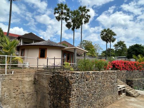 a house with a stone wall and palm trees at Villa Ponjok Batu Residence in Bukti