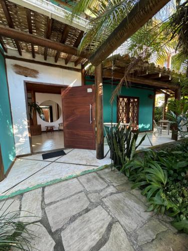 a house with a wooden door and a patio at Pouso Sabiá Suítes in Paraty