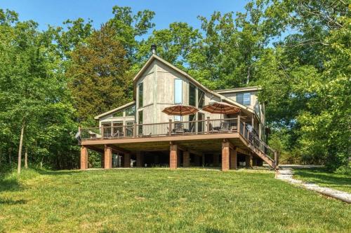 a large house with a deck on a grass field at Linden Lakefront Retreat with Kayaks in Innsbrook
