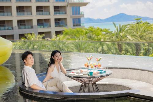 a man and a woman sitting at a table in the water at DoubleTree by Hilton Shanwei in Shanwei