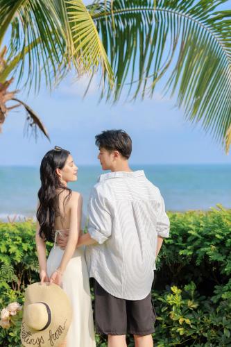 a man and a woman standing under a palm tree at DoubleTree by Hilton Shanwei in Shanwei