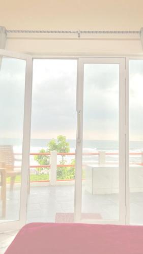 a room with sliding glass doors with a view of the ocean at vila La-surf in Padangnegeri