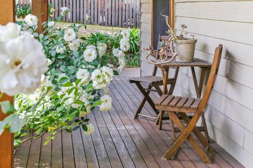 eine Veranda mit 2 Stühlen, einem Tisch und Blumen in der Unterkunft Spring Creek Cottage in Beechworth