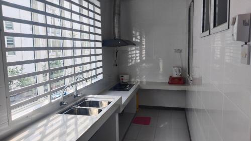 a white kitchen with a sink and a window at Happy inn home in Ipoh