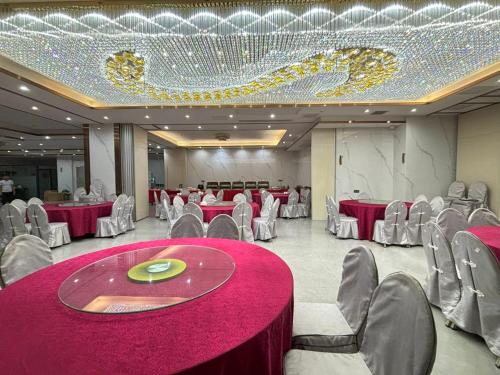 a banquet hall with red tables and chairs and a chandelier at Lido De Paris Hotel in Manila