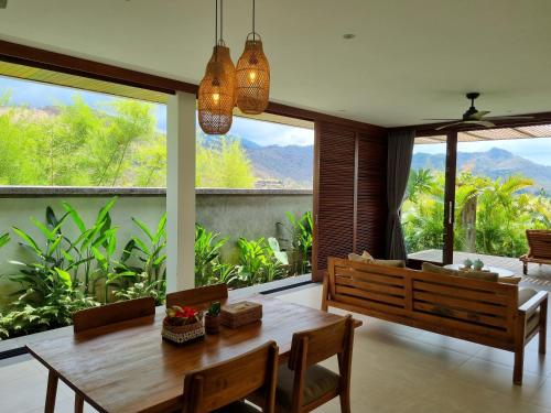 a dining room with a table and a large window at Sumberkima Resort in Pemuteran