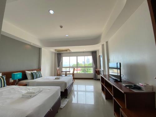 a hotel room with two beds and a television at KP Seaview Jomtien in Na Jomtien