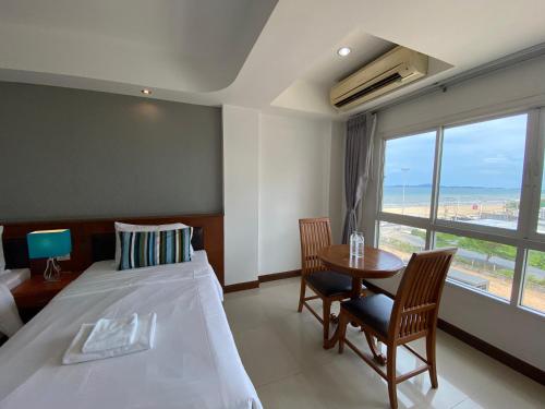 a bedroom with a bed and a table and a window at KP Seaview Jomtien in Na Jomtien