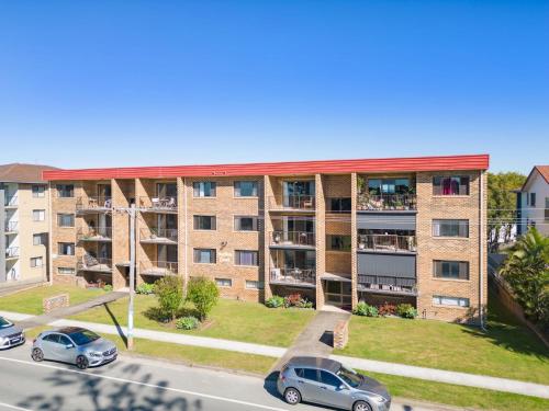 an apartment building with cars parked in front of it at Seaside Getaway on Kingscliff Beach in Kingscliff