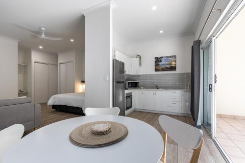 a white kitchen and living room with a table and chairs at Wave Break in Agnes in Agnes Water