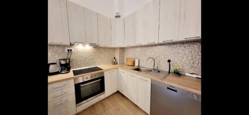 a kitchen with white cabinets and stainless steel appliances at Apartment Bregava in Stolac