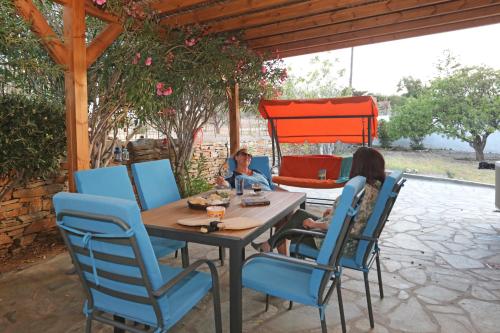 two women sitting at a table on a patio at Ruby's summer house with spacious garden and free parking in Gavrion