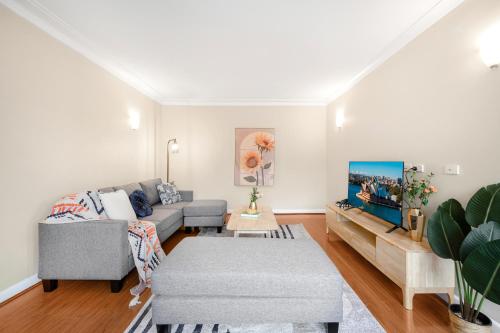 a living room with a couch and a tv at Bexley 5Br near Train & Shpping with pool 10ppl First Floor in Sydney