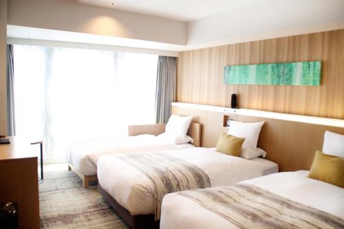 a hotel room with two beds and a window at Hotel GrandBach Sendai in Sendai