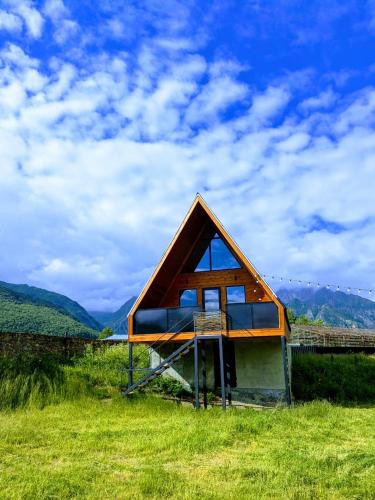 a small house with a roof on a grass field at Rest point cottage Kazbegi in Stepantsminda