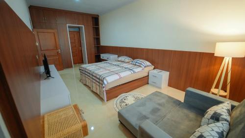 a small bedroom with a bed and a couch at Guest House Jogja Lempongsari in Kejayan