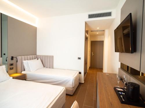 a hotel room with two beds and a flat screen tv at JOST Caravel in Vlorë