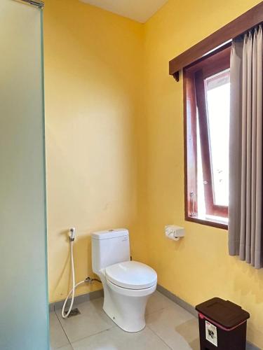 a bathroom with a white toilet and a window at Villa Ponjok Batu Residence in Bukti