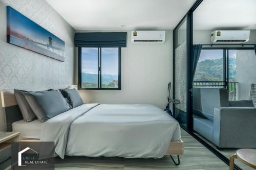 une chambre avec un lit, une chaise et des fenêtres dans l'établissement Cozy Studio Apartment at Naiyang Beach G507, à Phuket