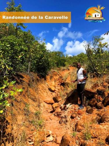 a person standing on a dirt hillside with at F2 Ixora - spa - piscine - vue mer - 9 min de la plage - Ti Zwézo Paradi in La Trinité