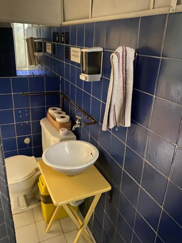 a blue tiled bathroom with a sink and a toilet at Hostel Home in Mexico City