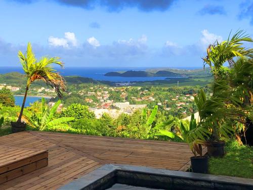 a wooden deck with a view of the ocean at F2 Ixora - spa - piscine - vue mer - 9 min de la plage - Ti Zwézo Paradi in La Trinité