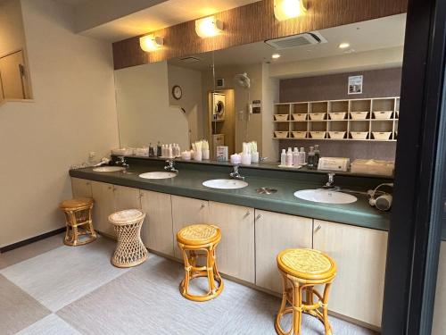 un bagno con tre lavandini e tre sgabelli di Hotel Route-Inn Kanazawa Ekimae a Kanazawa