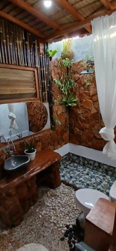 a bathroom with a stone wall with a sink and a toilet at Tropical Jungle lodge & Jungle trekking in Bukit Lawang
