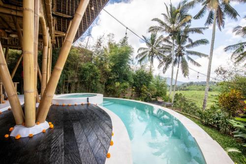 a swimming pool in a resort with palm trees at Magic Hills Bali - Eco Luxury Adventure in Karangasem
