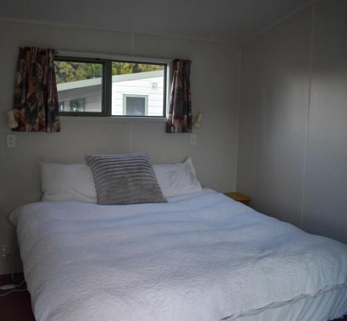 a bedroom with a white bed with a window at Route79 Holiday Park Geraldine in Geraldine