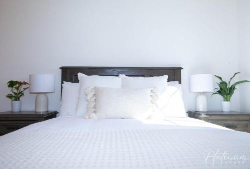 a bedroom with a white bed with two lamps at Glenare On Read in Horsham