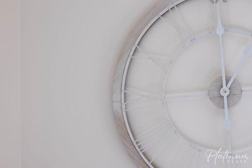 a white clock hanging on a wall at Glenare On Read in Horsham