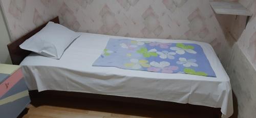a bed with a blue blanket with flowers on it at Guest House Nise in Tbilisi City